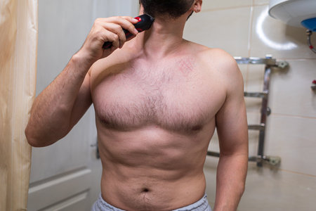 A man is getting ready to shave with a power loom. A man with an athletic figure in the bathroom.の写真素材