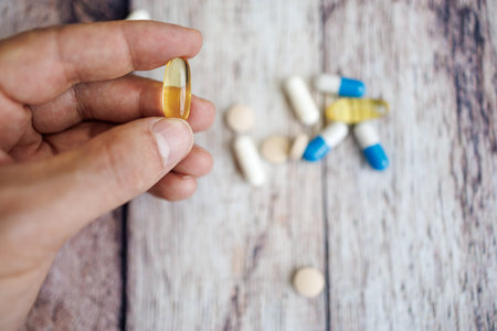 Fingers holding an omega capsule. nutritional supplements and vitamins.の写真素材
