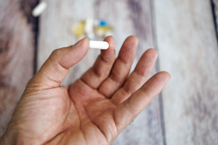 The fingers hold the capsule, nutritional supplements and vitamins.の写真素材