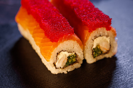 A set of delicious sushi rolls Close-up of Sushi rolls with red caviar on a black standの写真素材