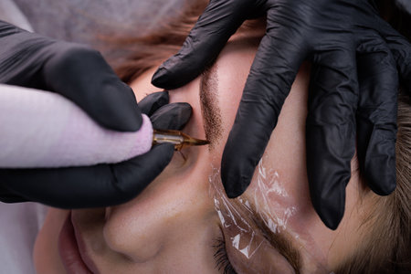 Injection of permanent eyebrow makeup into the skin of the eyebrows. PMU Procedure, Permanent Eyebrow Makeup.の写真素材