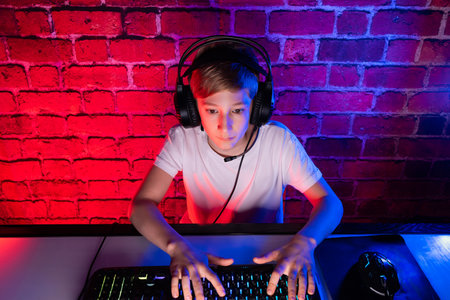 A teenager in a white t-shirt and headphones plays video games. A gamer boy plays computer games...