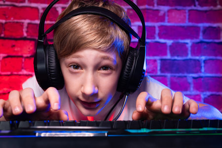 A teenager at a keyboard making faces playing computer games. A gamer boy plays computer games...