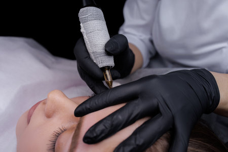 Completing permanent eyebrow makeup with a tattoo machine. PMU Procedure, Permanent Eyebrow Makeup.の写真素材
