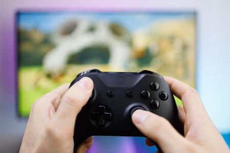 Pressing the sticks of a game gamepad in front of the monitor. Video game gamepad in hand