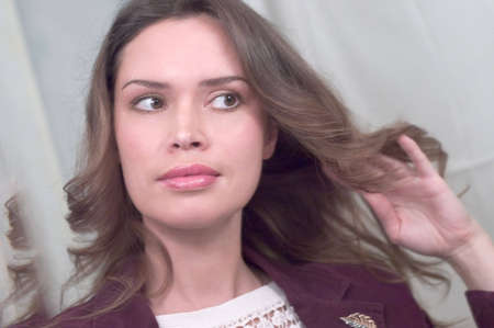 Brunette is posing in front of mirror styling her hair