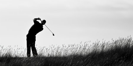 Monochrome Silhouette of Golfer Taking a Swing in Tall Grassの素材