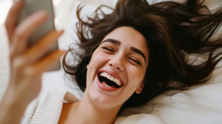 Joy in Simplicity: Young Woman Laughing While Holding a Phoneの素材