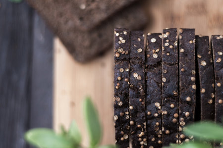 Slices of black bread with peppercorns and green leavesの写真素材