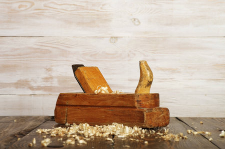 old planer and shavings on dark wooden table, white wallの写真素材
