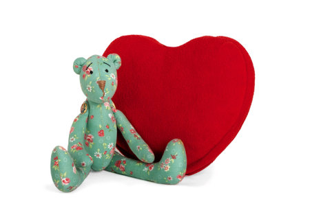 Green Teddy bear seating near big red heart, isolatedの写真素材