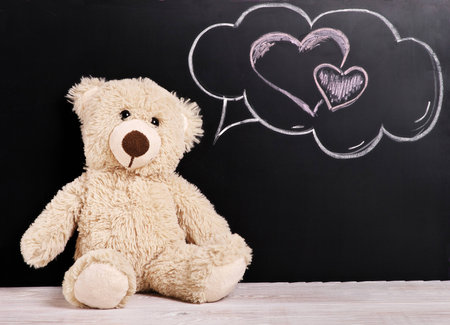 Teddy bear with thoughts of love near the chalk Boardの写真素材