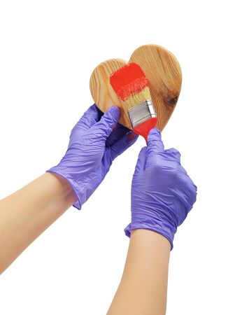 hand paints the heart with a brush
hand paint in red wooden heart
hand in blue glove holds a red brushの写真素材
