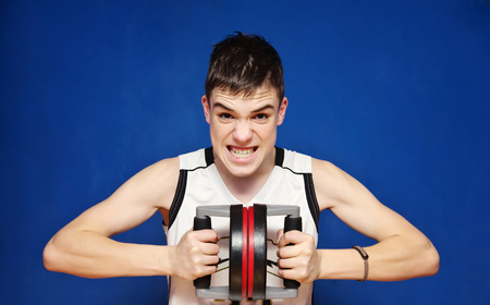 Pushup Bars Handles Stand. teen violently compresses the push-UP Bars. Blue Backgroundの写真素材