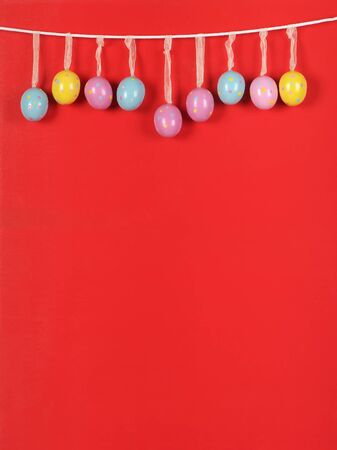 colorful Easter eggs on a rope. Red background. vivid colors of Easter eggs.の写真素材