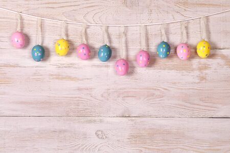 colorful Easter eggs on a rope. wooden wall. vivid colors of Easter eggs.の写真素材