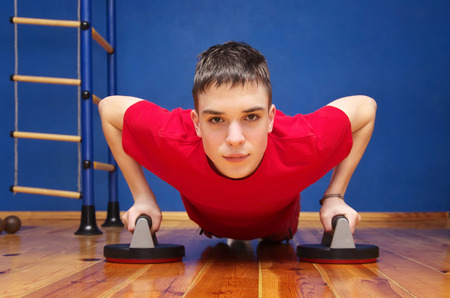 guy push-up from the floor. fitness at home. gym room. blue wall.の写真素材