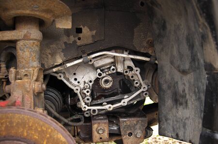 engine, engine mount and rusty brake disc on a broken car in the yardの写真素材