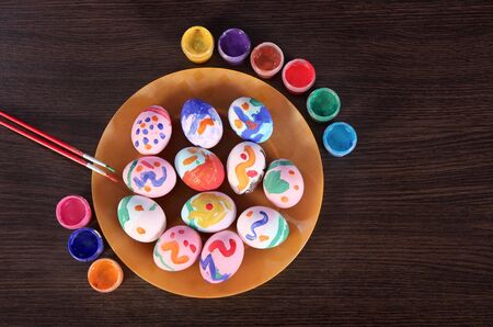 painted Easter eggs, paintbrush and paint on the table. preparation for Easter. dark wooden table.の写真素材