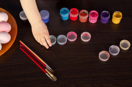 girl paints Easter eggs. hand, paintbrush and paint on the table. preparation for Easter. wooden table.の写真素材