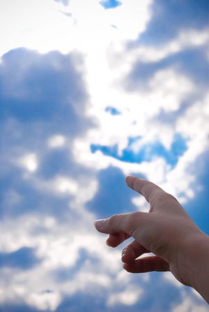 finger pointing at the blue sky with cloudsの写真素材