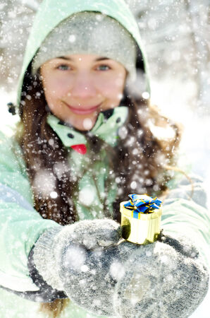 happy young woman in winter with a giftの写真素材