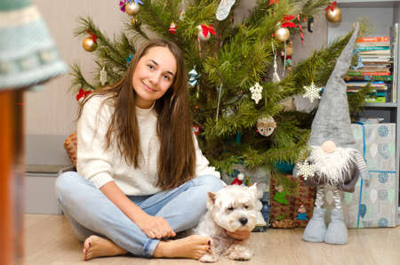 beautiful woman and dog sitting near christmas tree