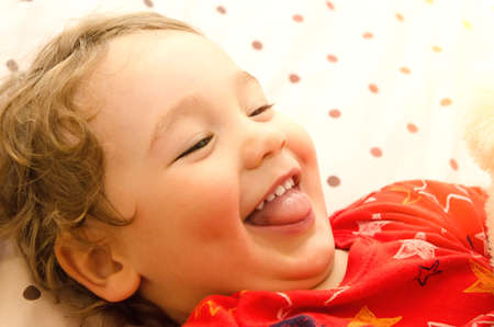 little boy smiling on the bedの写真素材