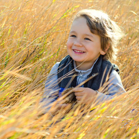little boy sitting in autumn fieldの写真素材