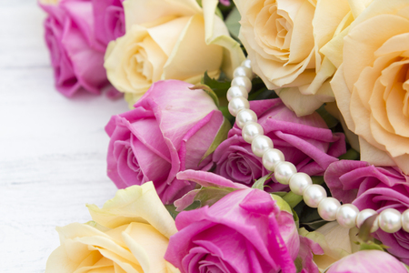 Beautiful roses on a white wooden background. Roses and pearls on a wooden backgroundの写真素材