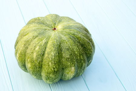 Green pumpkin on a turquoise wooden background