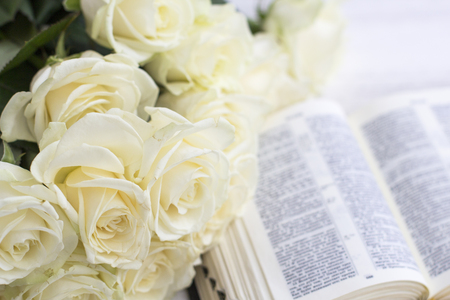 White roses and the Bible. White roses and the Bible on a white wooden background