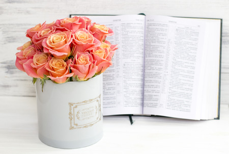 Roses in a round box and the Bible. Beautiful pink roses on a white wooden background. Beautiful...