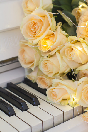 Peach roses with garlands on a white pianoの写真素材