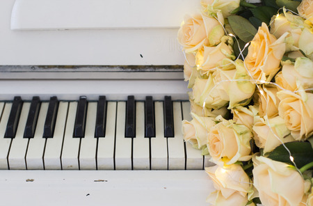 Peach roses with garlands on a white pianoの写真素材
