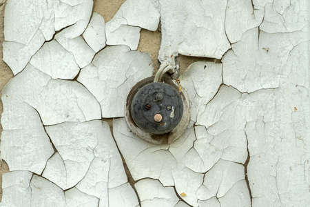 Black vintage light switch on the old wall with peeling white paint