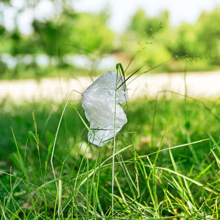 Used plastic bag dumped on the green grass in the park. Environmental pollution pollution concept.の写真素材