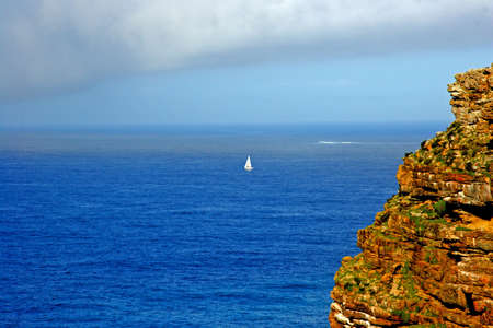View of the sea with a sailboat and a mountain.の写真素材