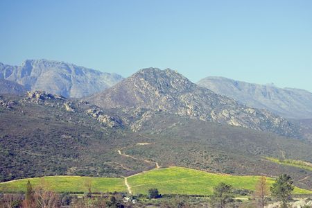 Mountains surrounding by green fields with a clear view of a road.の写真素材