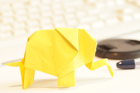 Paper origami elephant isolated on white background on the table next to the computer keyboardの写真素材