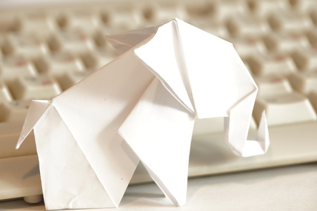 Paper origami elephant isolated on white background on the table next to the computer keyboardの写真素材