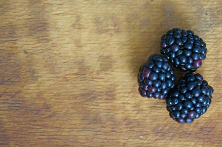 Ripe and juicy blackberries isolated on a wooden background.の写真素材