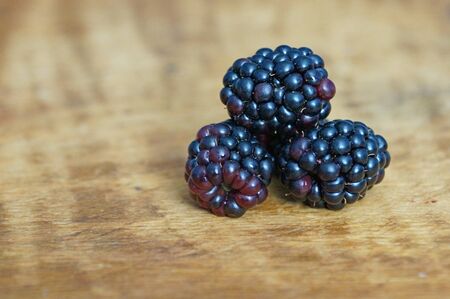 Ripe and juicy blackberries isolated on a wooden background.