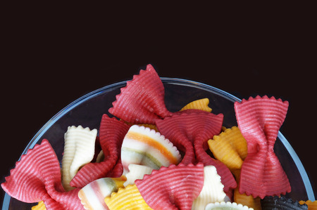 Multicolored pasta. Beautiful pasta in the form of a butterfly. Original italian pasta isolated on a black background. Figured pasta on a black background.の写真素材