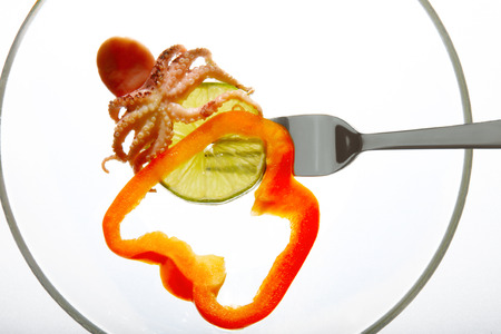 raw octopus ingredient isolated on fork white background lime sliceの写真素材