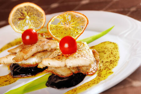 A pieces of fried fish served on plate isolated, with lemon and sauceの写真素材