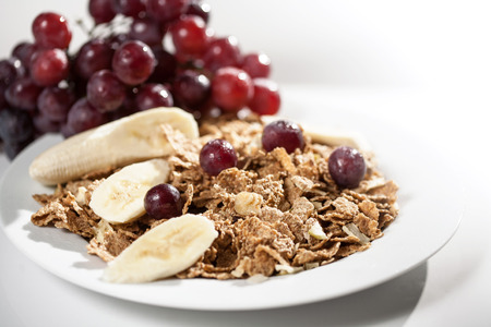close up muesli with strawberry and grape macro photo over white background