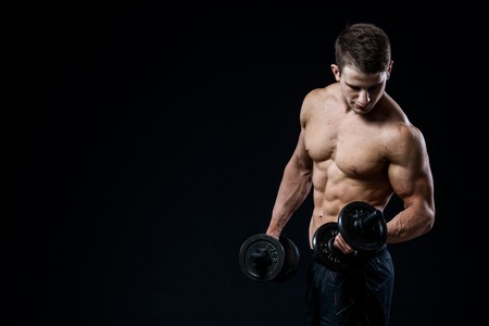 Man showing his six pack abs on dark backgroundの写真素材