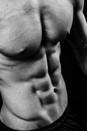 Dark contrast shot of young muscular fitness man stomach and arm.の写真素材