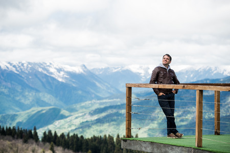 Man at view point in the mountains. Happy and smiling, looking to the skyの写真素材